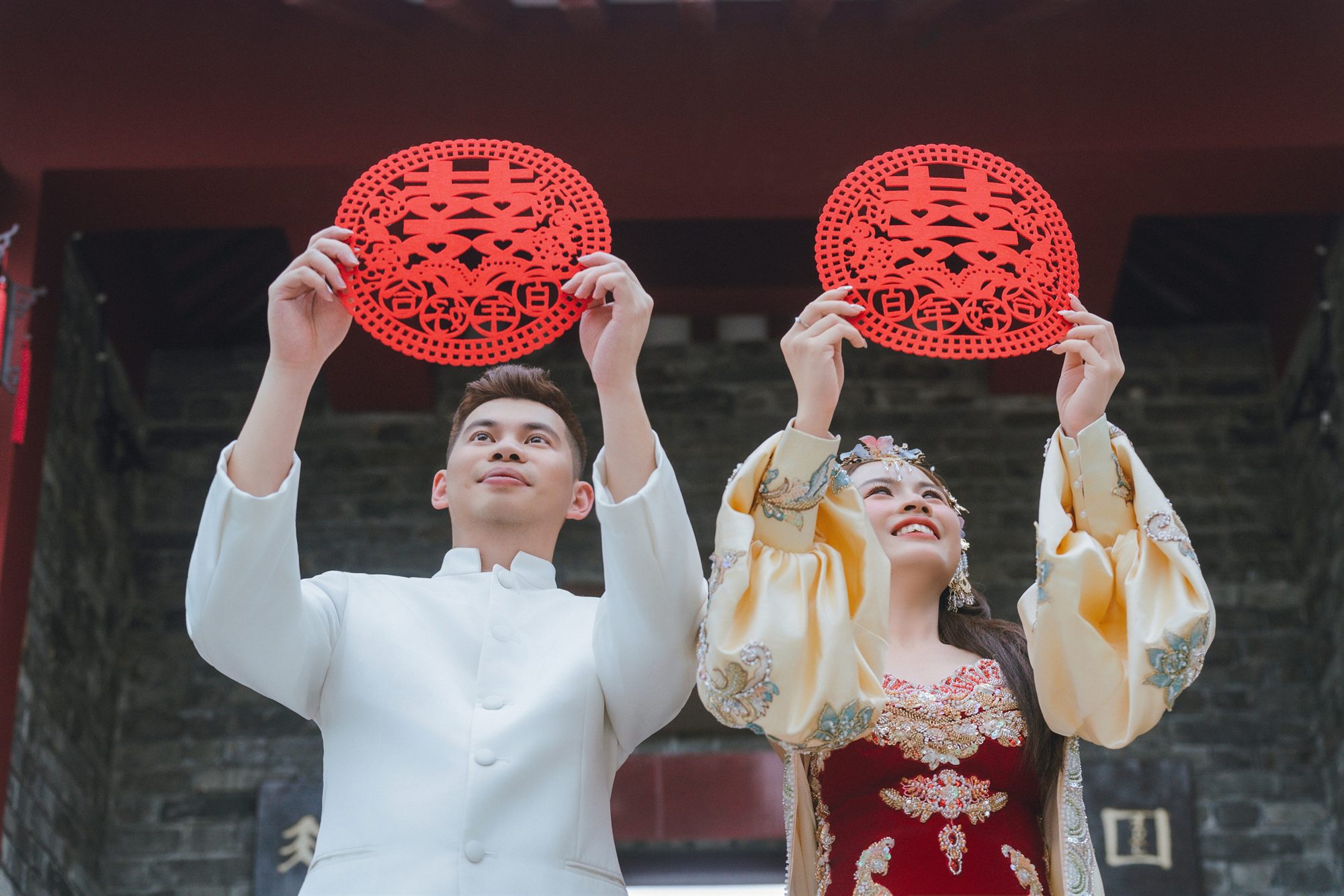 Lucas Lok and Ting Ting holding up red double-happiness paper cuts